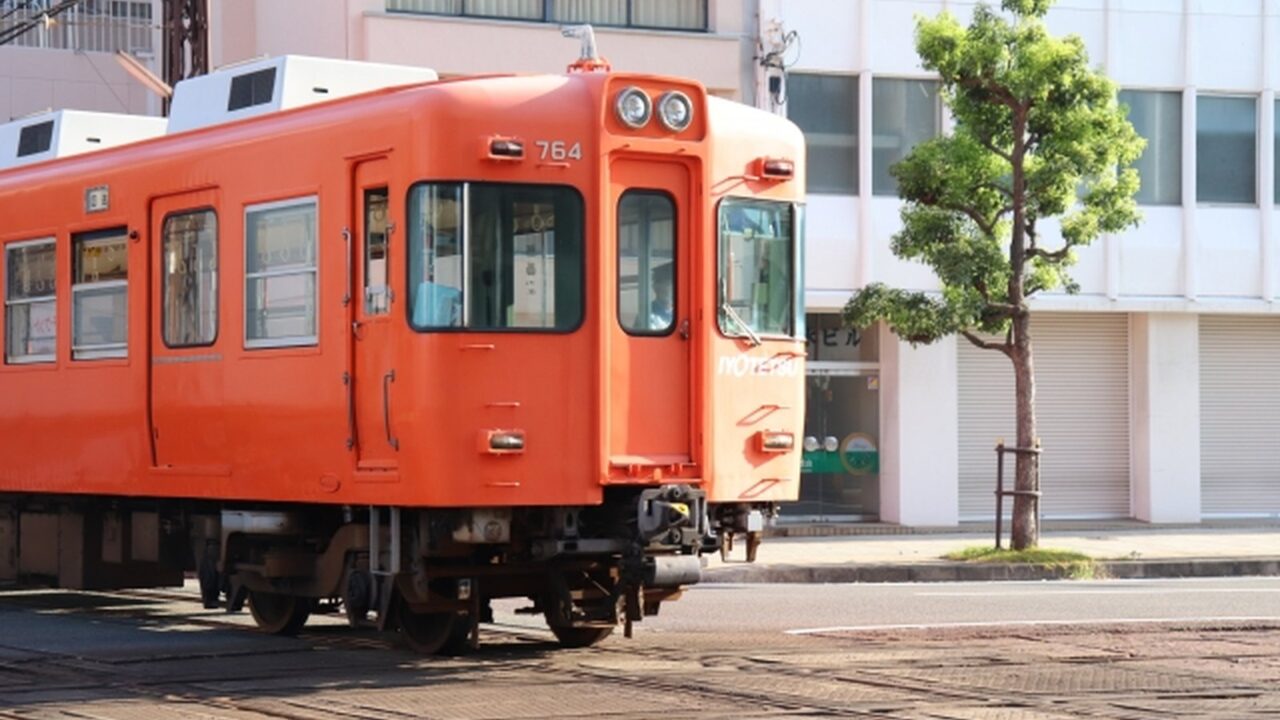 伊予鉄700系さよならイベント2026|ラストランの申込方法・料金・抽選日程 1 オレンジ色の伊予鉄道700系764号車を線路脇から撮影した実写